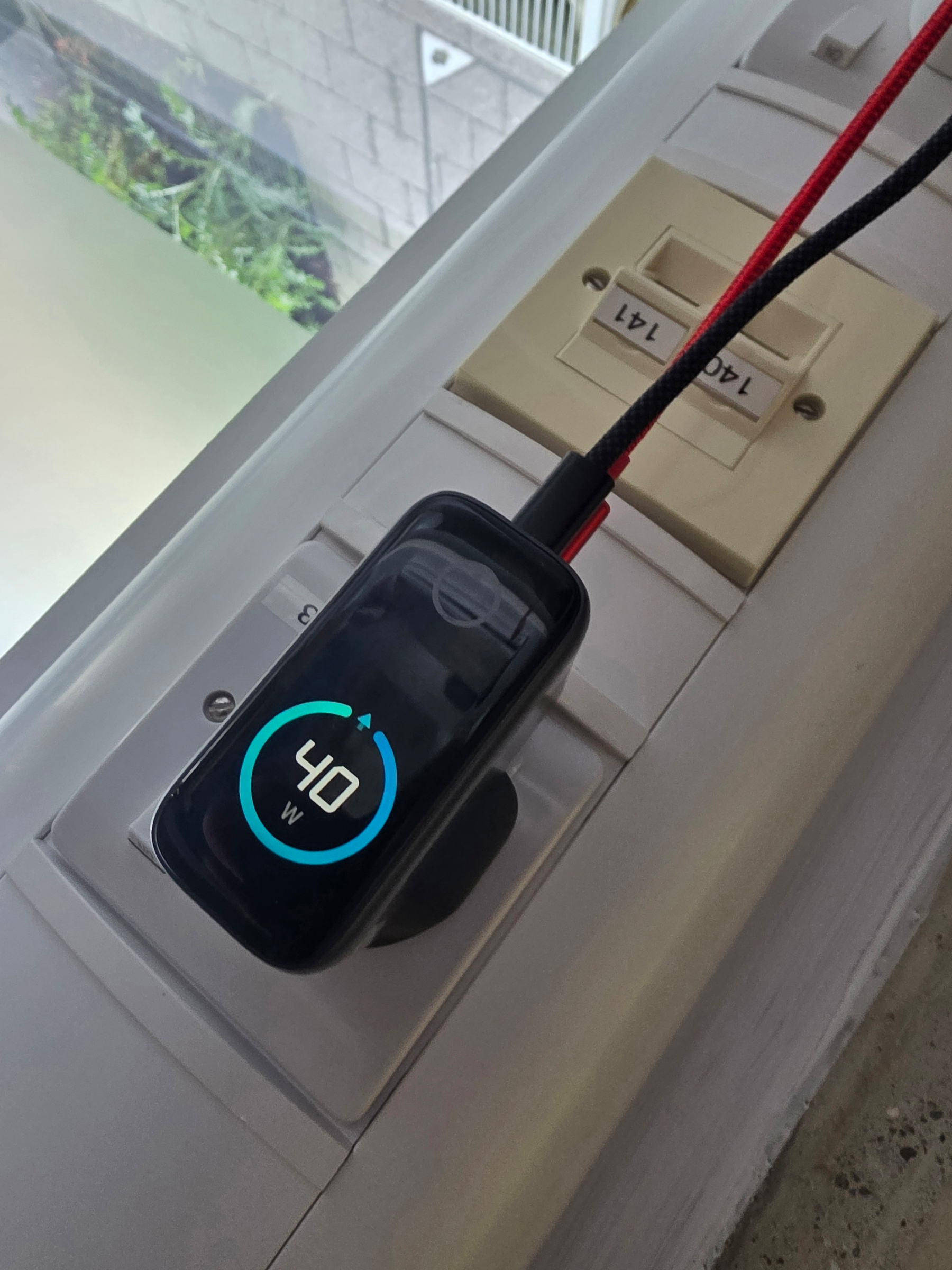 Anker Smart Charger displaying 40 watts is connected to a power strip with labeled sockets.